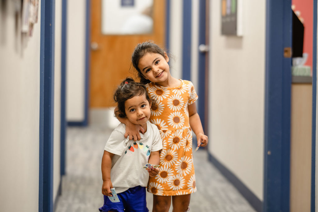 two young girls standing in a hallway