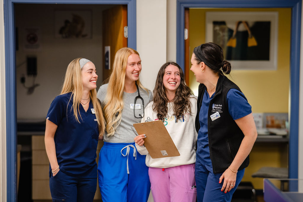 a group of four women medical providers laughing together