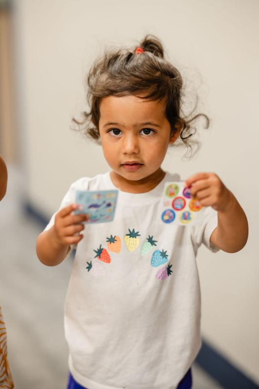 a young girl holding up stickers